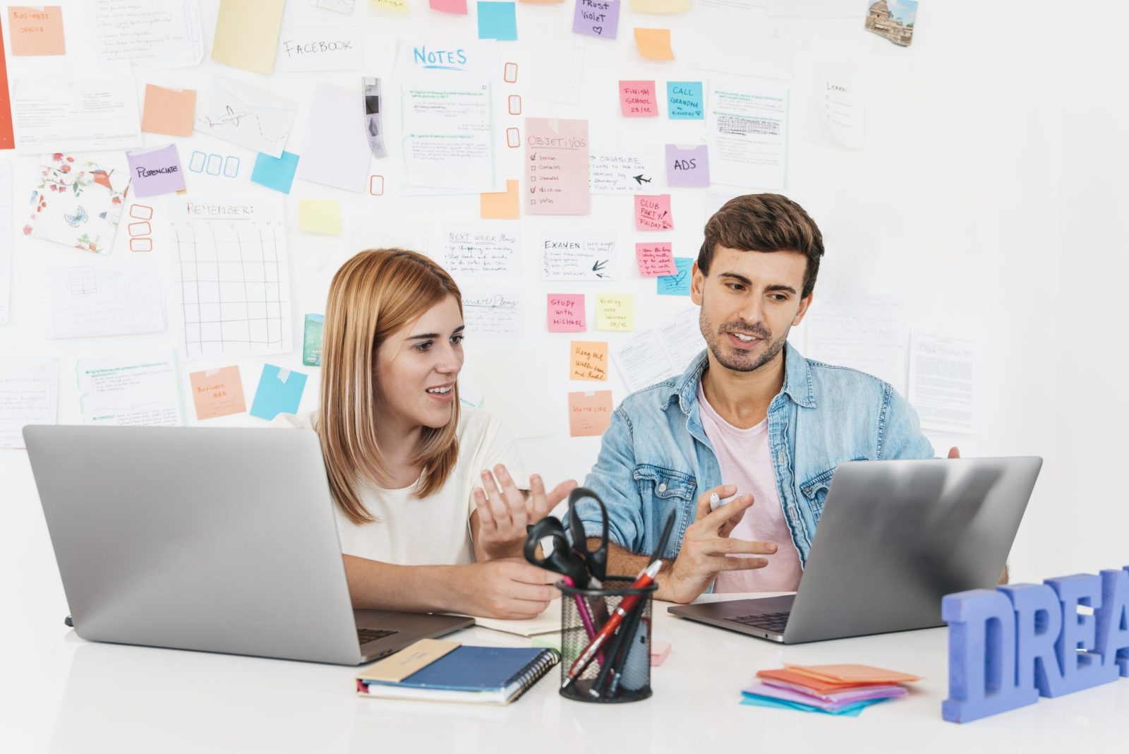 Smiling Male Female Sitting Desk Talking Looking Laptop Scaled 1600x1068